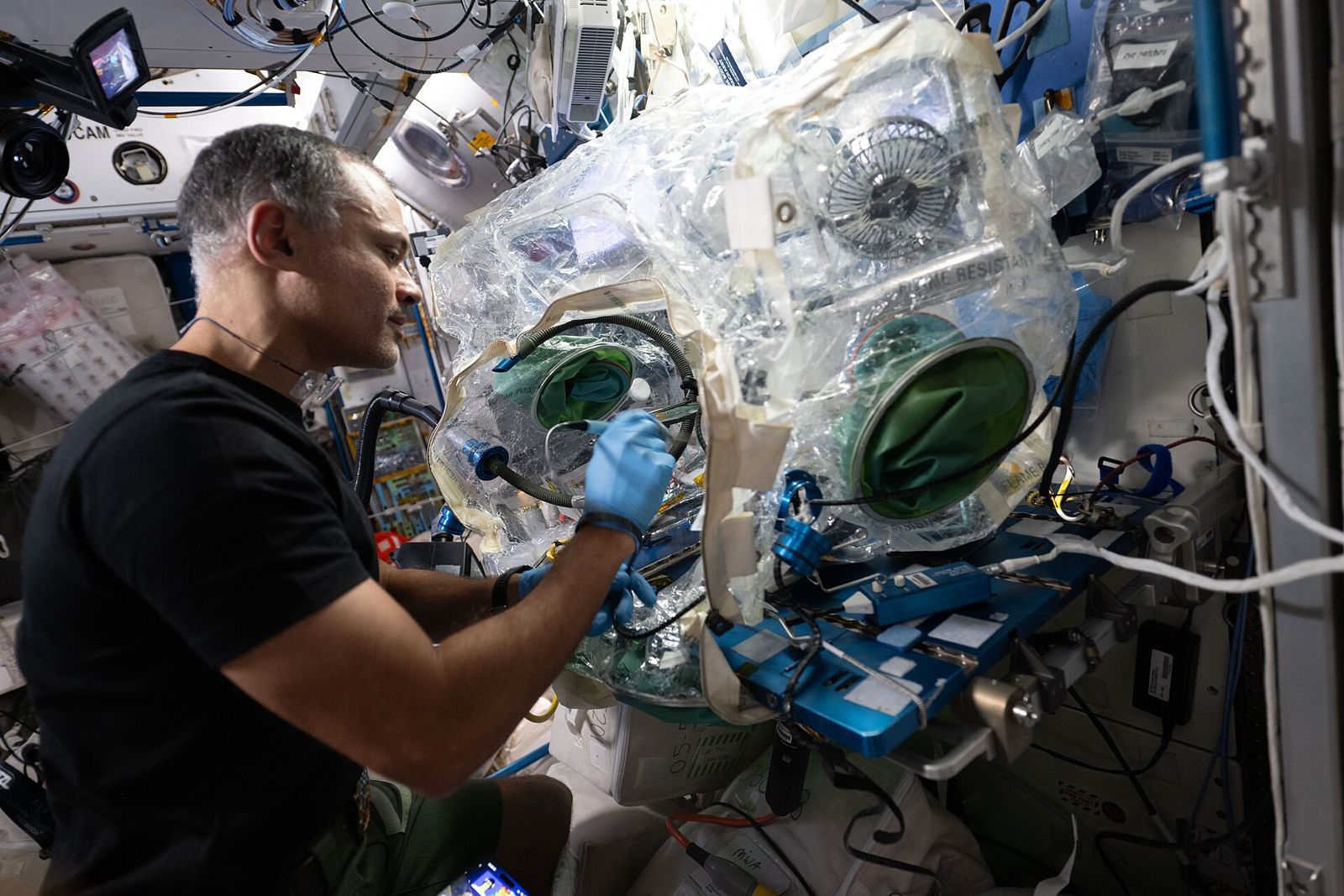 Engineer soldering a circuit board inside a sealed workstation